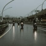 Skuterzyści jadą po mokrej autostradzie w deszczu pod ciemnym niebem