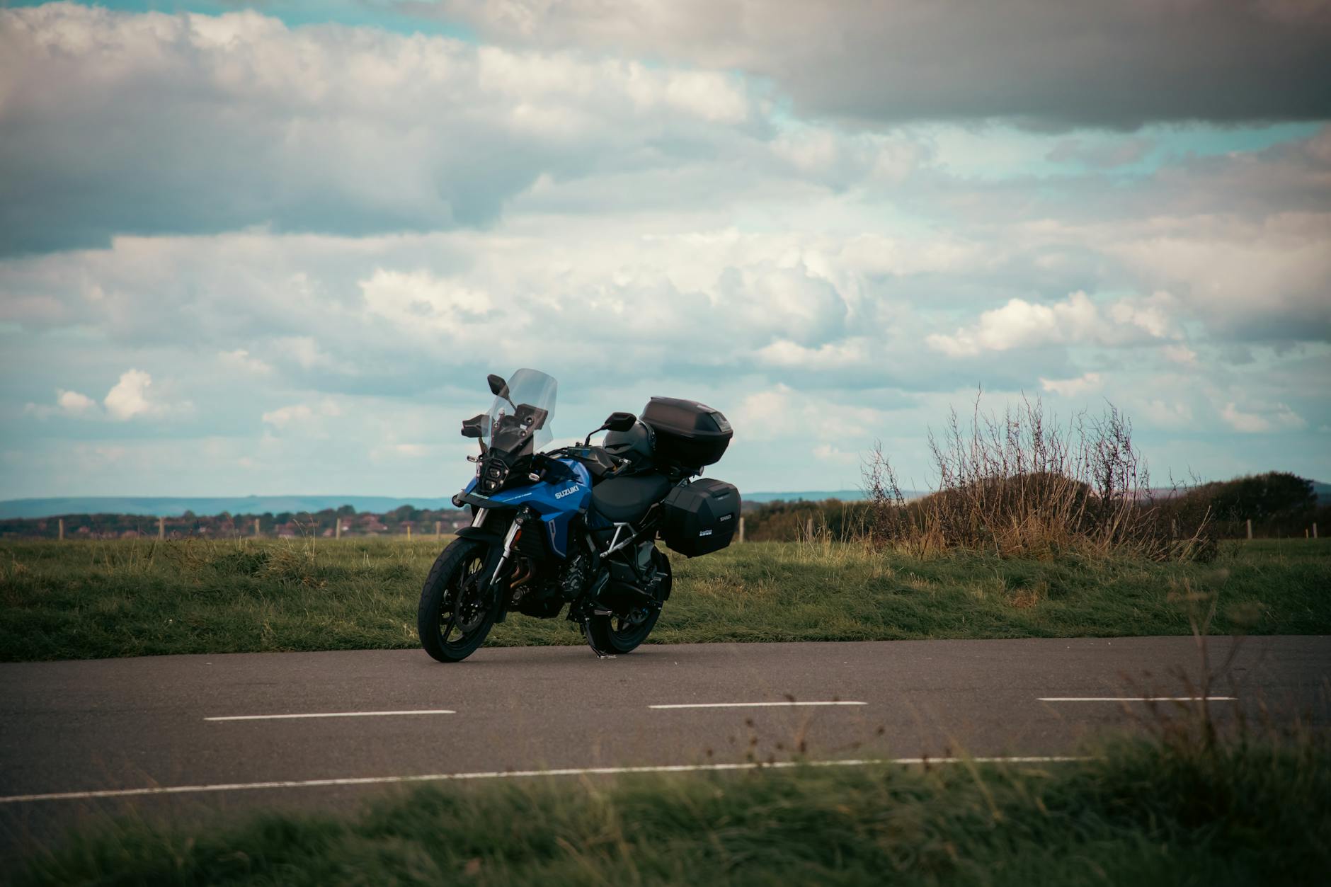 Motocyklowa pętla po Kaszubach: widoki, zakręty i miejsca na przerwę Niebieski motocykl zaparkowany na wiejskiej drodze pod zachmurzonym niebem