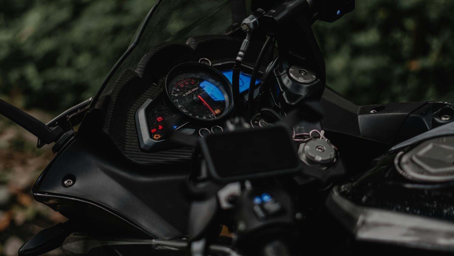 Zbliżenie na cyfrowy kokpit motocykla i przyciski na kierownicy